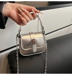 Detail of silver metallic mini bag featuring a decorative C-letter round metal seal
