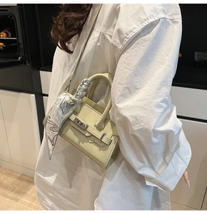 Detail der pistaziengrünen Mini-Ledertasche mit Seidenschal-Griff und Drehverschluss