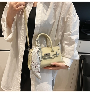 Detail der hellgrünen Lackledertasche mit Seidenschal am Griff und Metalldrehverschluss