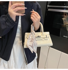 Detail der cremefarbenen Lackledertasche mit Seidentuchgriff und Metallverschluss