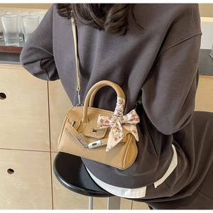 Detailansicht einer kamelfarbenen Lederhandtasche mit Seidentuch und Silberbeschlägen