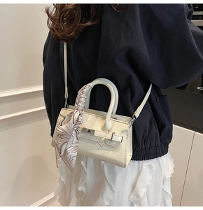 Detail der cremefarbenen Mini-Handtasche mit silbernem Drehverschluss und bedrucktem Seidenschal