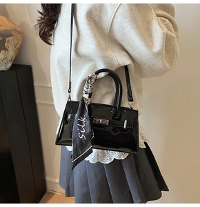 Detailansicht der schwarzen Lackledertasche mit Silberverschluss und Seidenschal-Akzent