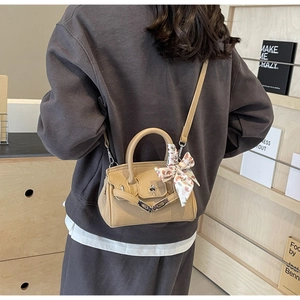 Detail der aprikosenfarbenen Ledertasche mit floralem Seidentuch und Metallverschluss