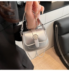 Detail showing the silver mini square bag with a metallic finish and metal chain strap
