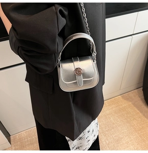 Detail view of mini silver bag with metallic texture and circular C buckle hardware