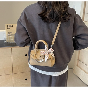 Detail der kamelfarbenen Ledertasche mit seidenschal-umwickeltem Griff und Schloss