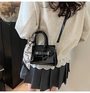 Detail der schwarzen Lackledertasche mit Seidentuch am Griff und Metallschnalle