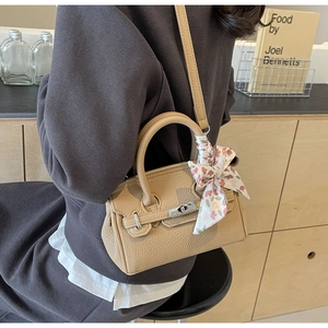 Detail der beigen Mini-Handtasche aus Narbenleder mit floralem Seidentuch am Griff
