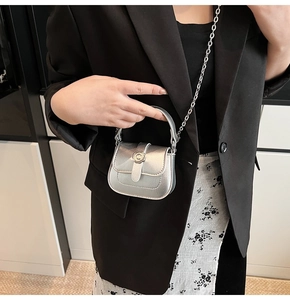 Macro detail of mini silver metallic bag featuring a C-shaped clasp and chain strap