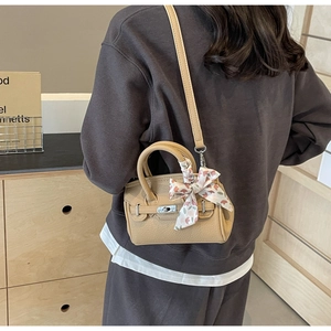 Detail einer aprikosenfarbenen Mini-Handtasche aus Leder mit gebundenem Seidentuch