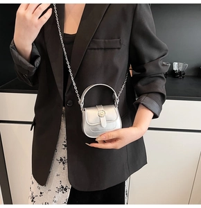 Close-up of a silver mini crossbody bag with a round metal buckle and chain strap