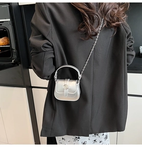 Close-up of a silver mini chain bag on a model, highlighting the metallic texture and clasp