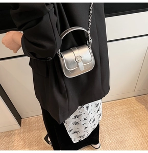 Detail of silver mini square bag with C buckle and metal chain strap on black blazer