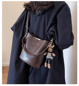 Detail of vintage dark brown bucket bag with thick chain and cute rabbit plush charm
