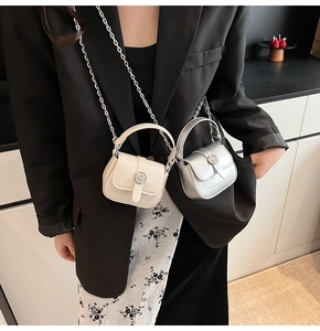 Model wearing a mini square leather bag in cream and silver with fine chain strap