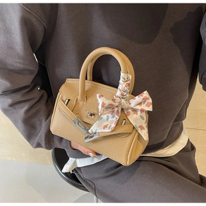 Detailansicht der khakifarbenen Ledertasche mit floralem Seidentuchgriff und Metallverschluss