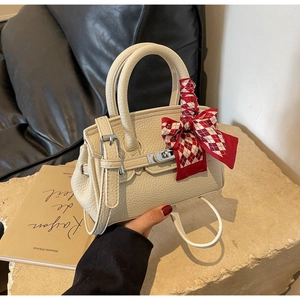 Detailansicht cremefarbene Lederhandtasche mit rot-weißem Seidentuch am Griff