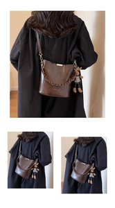 Detail of dark brown vintage bucket bag with decorative chain and cute bunny charm accessory