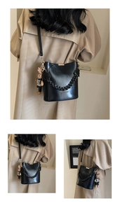 Detail of black washed PU leather bucket bag with thick chain and bunny charm