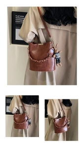 Detail of vintage brown leather bucket bag featuring woven handle and cute rabbit charm