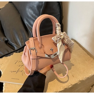 Detail der rosa Handtasche aus Leder mit dekorativem Seidenschal und silberner Schnalle