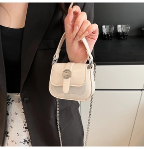Detail of mini white square bag with textured finish, floral buckle, and chain strap