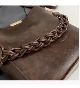 Close-up of brown PU leather bucket bag with woven handle and gold metal detail