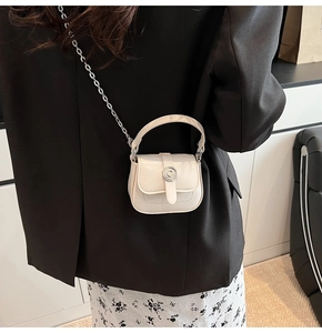 Close-up of mini ivory crossbody bag with vintage round metal buckle and chain strap