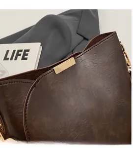 Close-up of vintage brown leather bucket bag with premium gold buckle and textured PU fabric