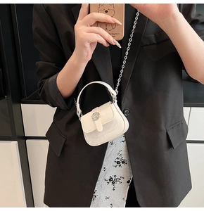 Close-up of white mini square bag with lychee texture and round metal buckle detail