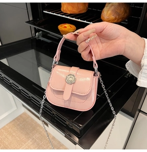 Detailed shot of a pink mini crossbody bag with glossy finish and floral metal buckle