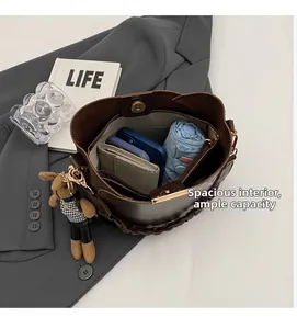 Detail view of large capacity dark brown bucket bag interior with accessories and bear charm