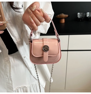 Macro view of a light pink mini saddle bag featuring a textured finish and silver C buckle