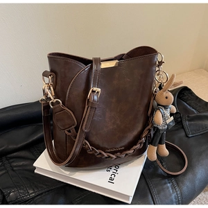 Detailed view of dark brown bucket bag with water ripple texture and golden hardware