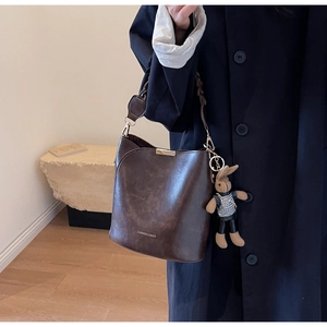 Detail of dark brown vintage bucket bag with leather texture and cute rabbit charm