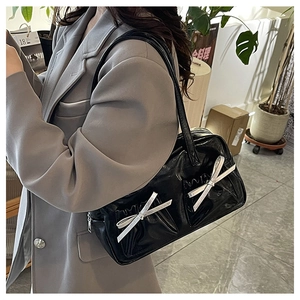 Shoulder shot of large black glossy tote bag with stylish bow knots and pleated texture