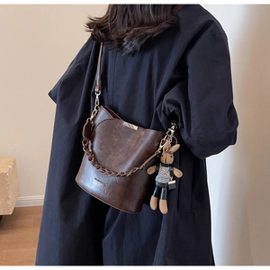 Detail of dark brown vintage bucket bag with chain strap and cute bunny doll charm