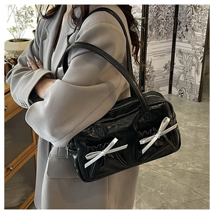 Detail of glossy black tote bag with white bows and textured front pockets