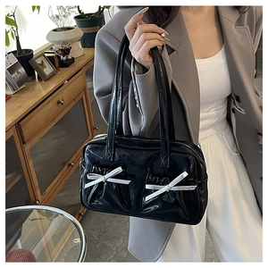 Detail of black glossy faux leather tote bag with silver bow accents and wrinkled texture