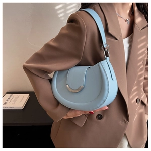 Gros plan d'un sac selle bleu clair avec garniture argentée porté par un mannequin