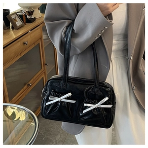 Detail of black glossy bow tote bag with long shoulder straps for elegant daily wear