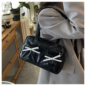 Detail of black glossy tote bag featuring white bow-knot pockets and zipper closure