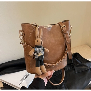 Detail of vintage brown bucket bag with gold buckle and cute rabbit pendant charm