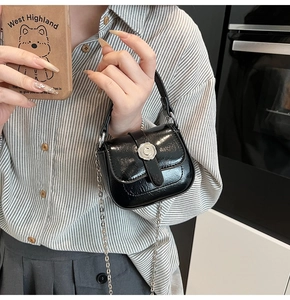 Close-up of a mini black glossy leather bag with silver camellia flower buckle detail