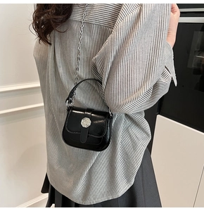 Close-up of black glossy mini square bag featuring silver round buckle and chain strap
