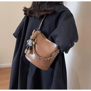 Detail of brown leather bucket bag with fashion text and cute rabbit charm on model