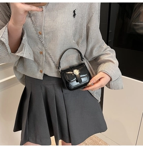 Close-up of black glossy mini bag with silver chain strap and metal relief buckle