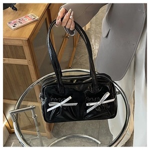 Close-up of black glossy patent leather tote with stylish silver bow decorations