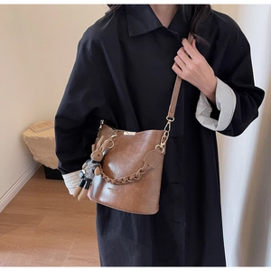 Detail of vintage brown leather bucket bag with braided chain and rabbit charm pendant